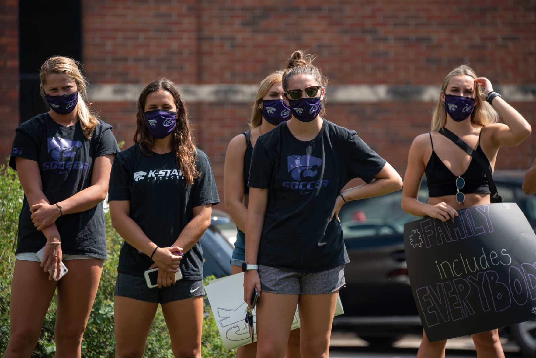 From left, Shae Turner, Brookelynn Entz, Maguire Sullivan, Shelby Lierz and Emily Crane listen to Miranda Urban speak at Triangle Park on Saturday.